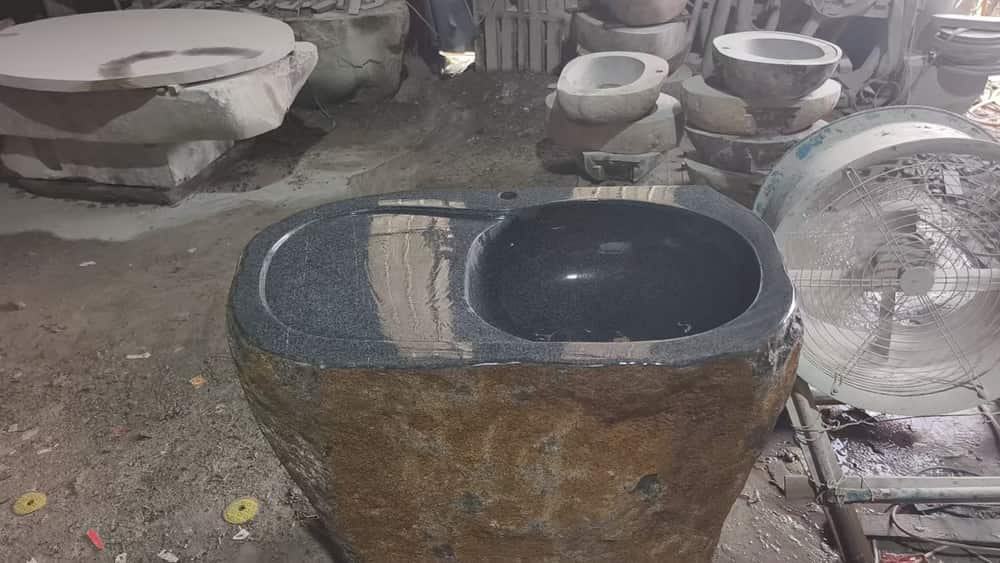 Dark natural stone wash basin with integrated drainboard in the workshop