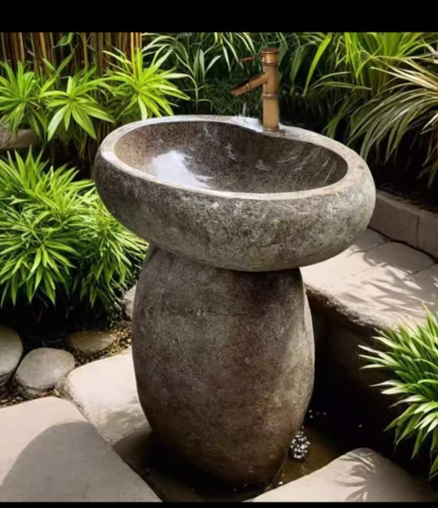 Round stone pedestal wash basin installed in a landscaped garden