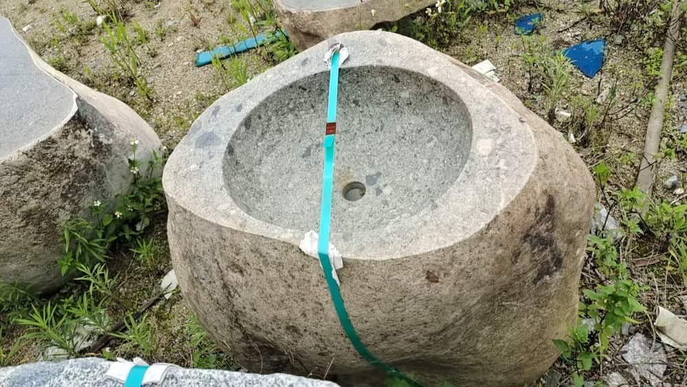 Round rustic natural stone basin with smooth bowl and hose