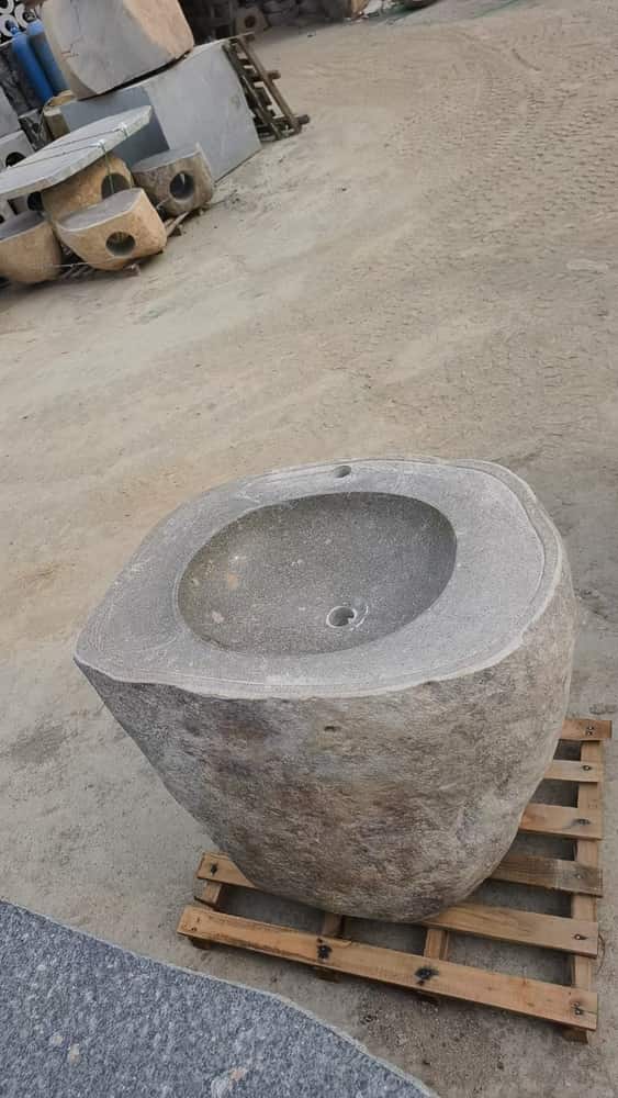 Round natural stone wash basin with drain opening prepared on a pallet